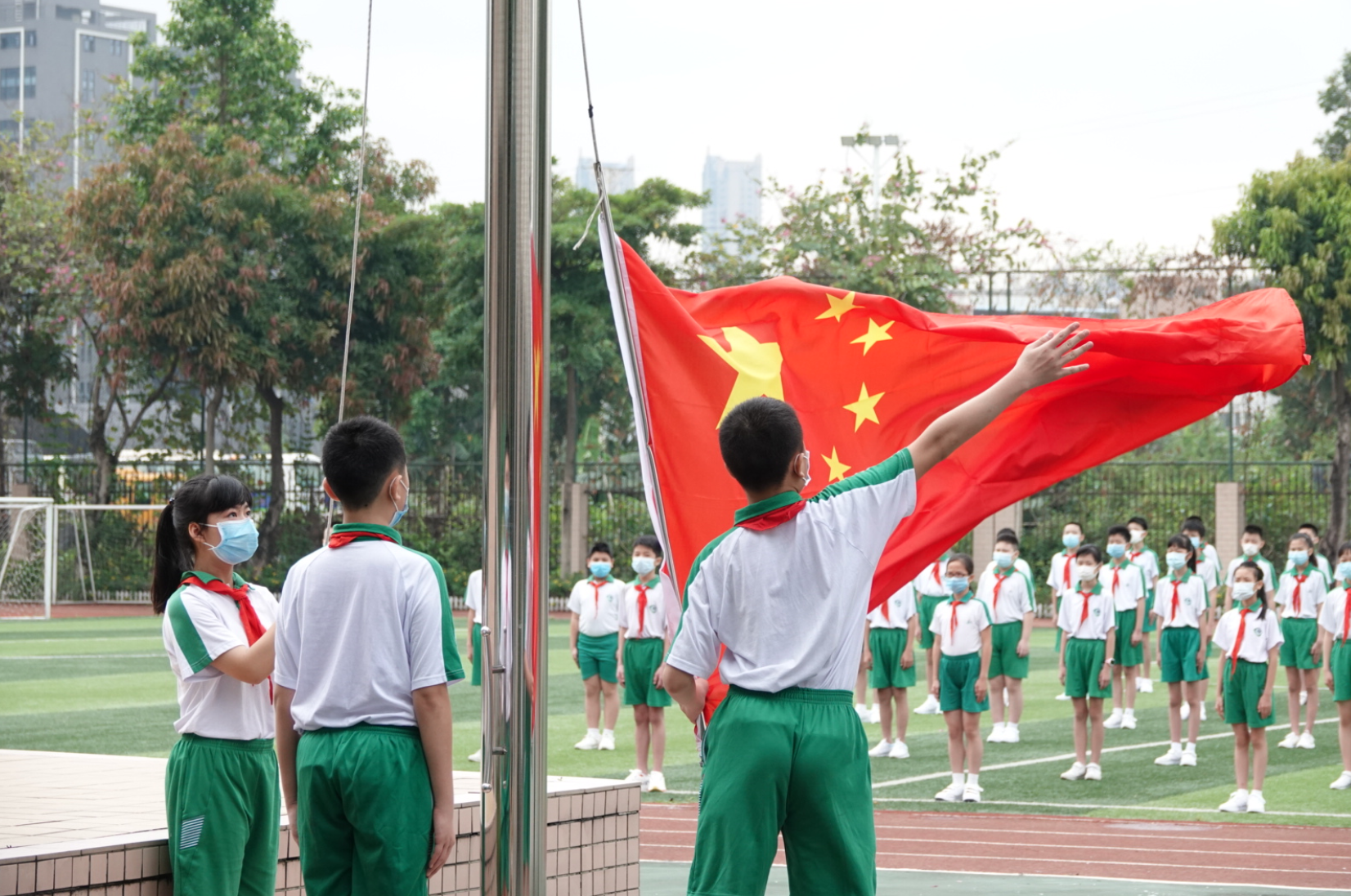 南武实验小学升旗仪式,同学们面向教室内的国旗行注目礼,唱国歌