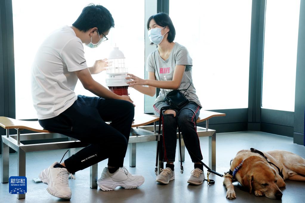 在香港海事博物館,視障人士蔡樂詩(右)在王瑋樂的引導下觸摸一個燈塔三維模型,用手感受燈塔模型的輪廓和結構(2021年10月19日攝)。新華社記者 王申 攝