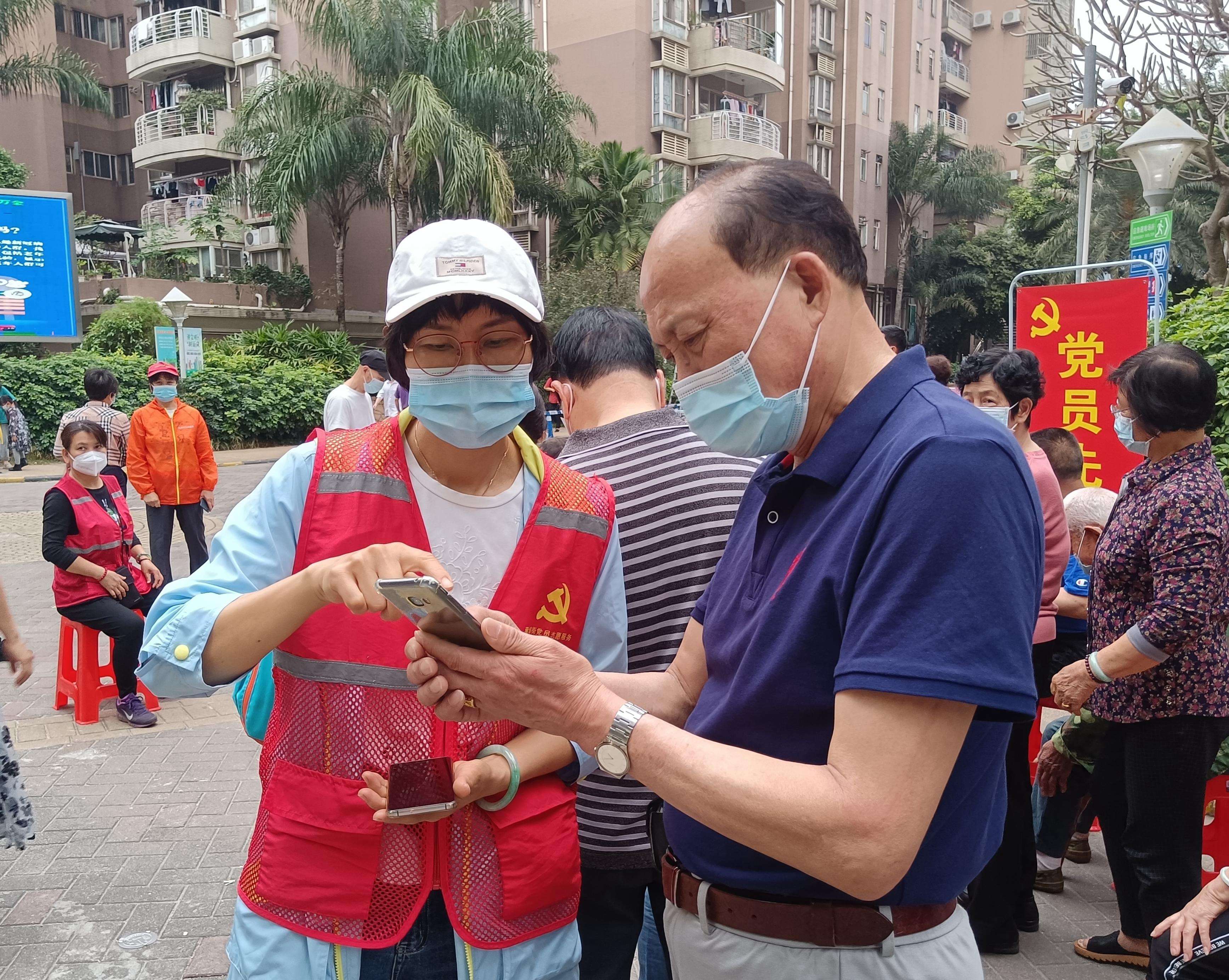 广州市黄埔区黄埔街道核酸检测点,党员志愿者正在协助检测居民登录电子系统