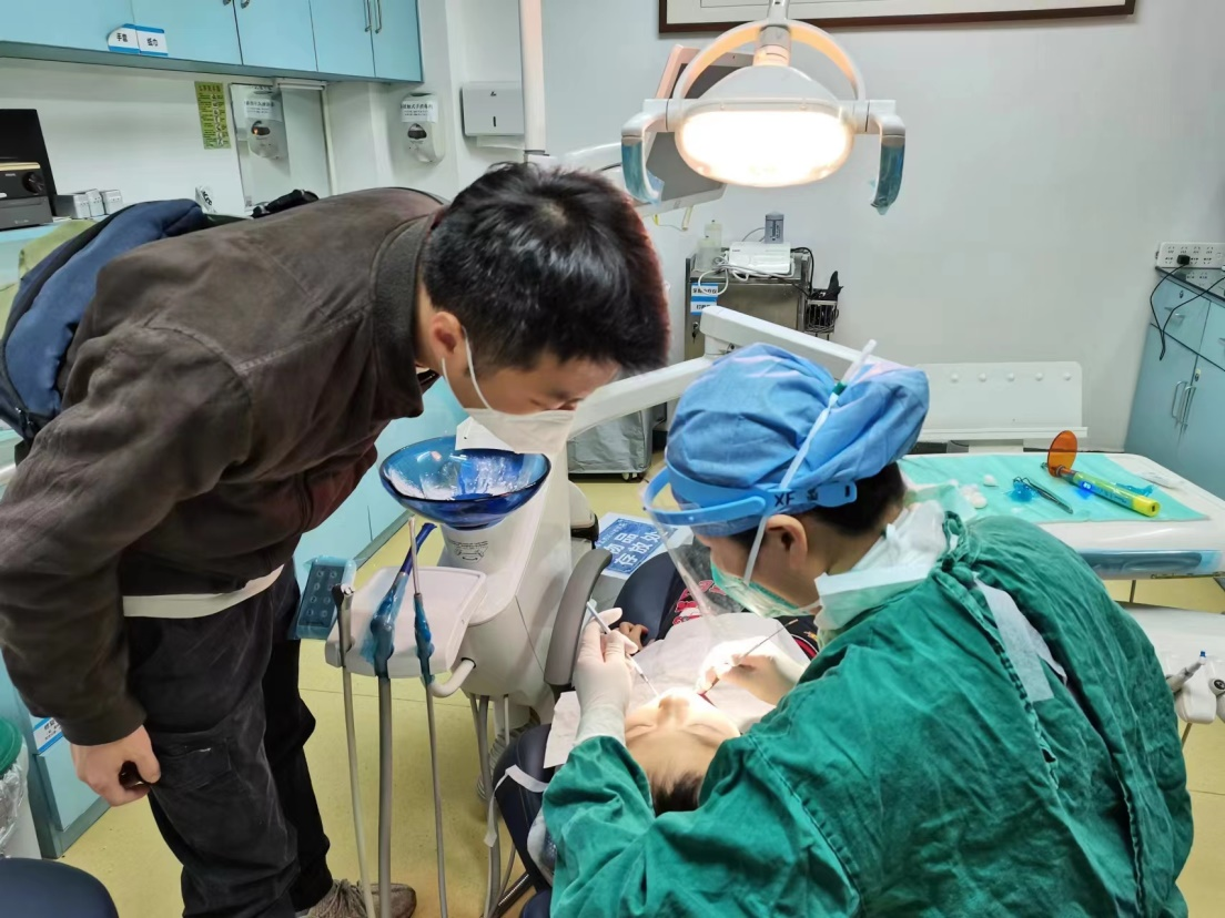 (图:医生和学生进行一对一口腔卫生宣教)