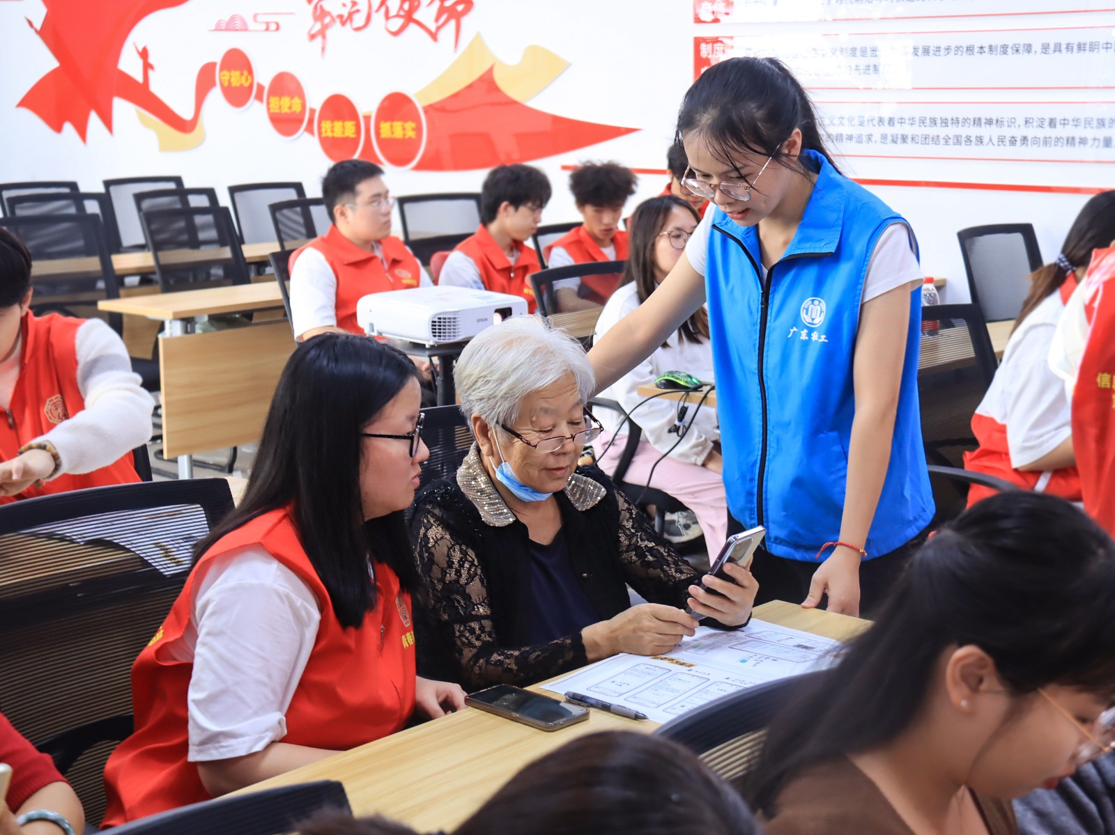 大学生志愿者和社区工作人员教阿姨使用智能手机。(来源:凤凰街道办事处)